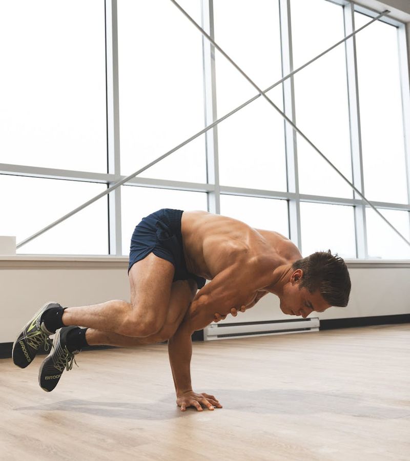 Man performing a controlled strength exercise in a dark room.